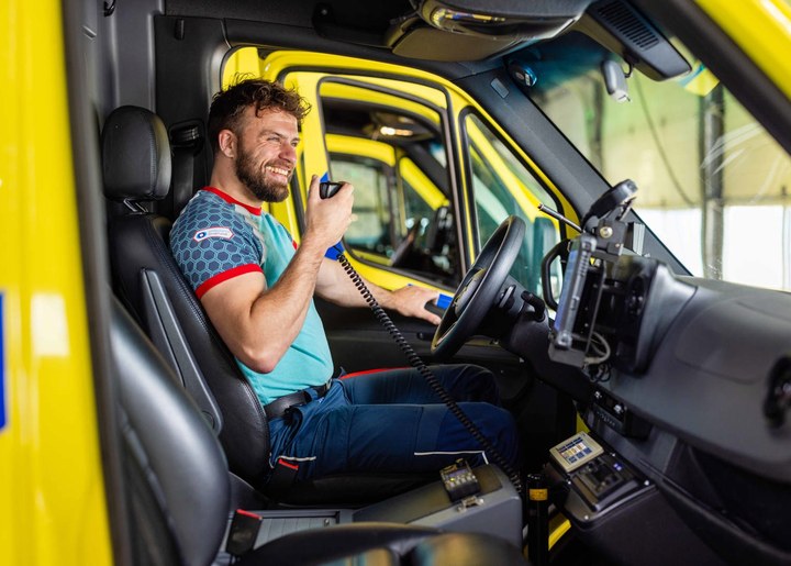 Ambulancechauffeur van Ambulance IJsselland met portofoon in de cabine